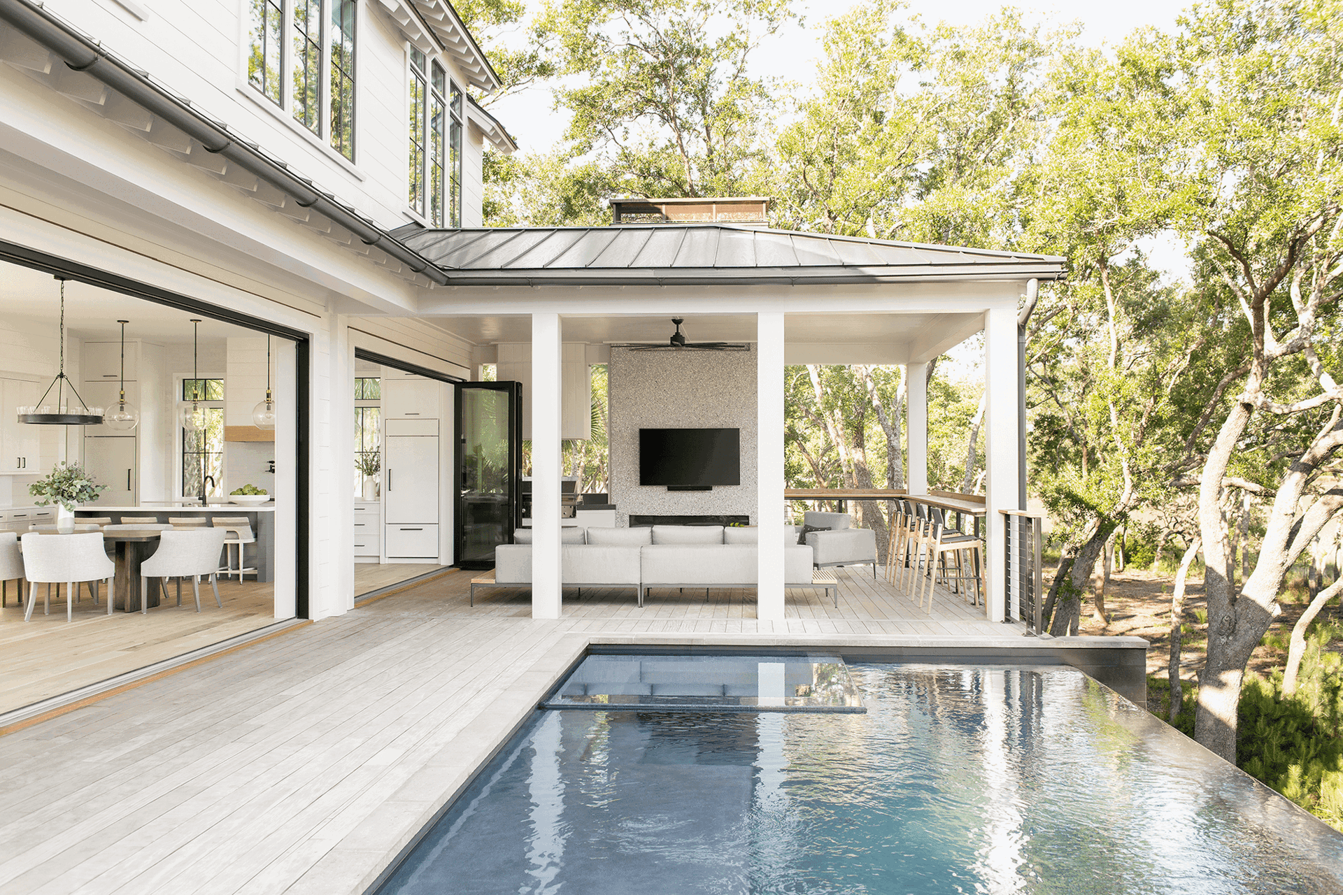 Large aluminum folding door system connecting modern home interior to outdoor pool terrace.